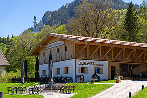 Exterior view of the Dorfwirt building and Neuschwanstein Castle in the background